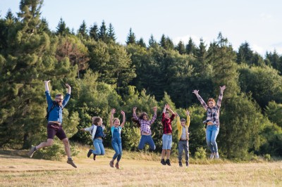 Gruppe von Schulkindern mit Lehrer auf Exkursion in der Natur, Springen.